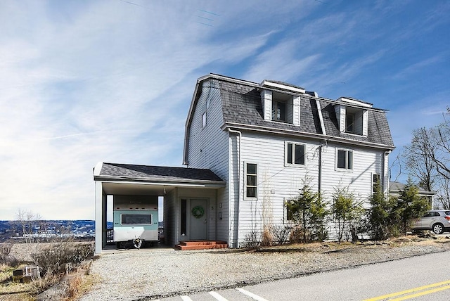 view of home's exterior featuring a gambrel roof, driveway, and a shingled roof