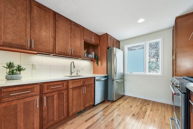 kitchen featuring brown cabinets, a sink, tasteful backsplash, appliances with stainless steel finishes, and light countertops