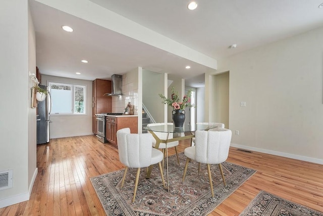 dining space with visible vents, baseboards, light wood-style flooring, and stairs