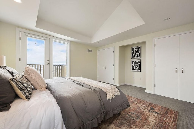 carpeted bedroom with access to exterior, visible vents, baseboards, a tray ceiling, and vaulted ceiling