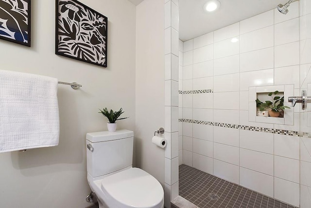 bathroom featuring toilet and a tile shower