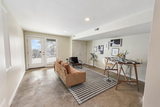 living area featuring visible vents, french doors, unfinished concrete flooring, and baseboards