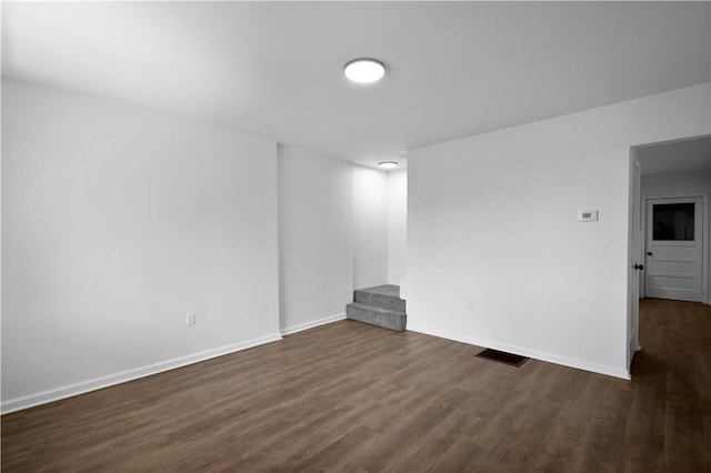 unfurnished room with visible vents, stairs, dark wood-type flooring, and baseboards