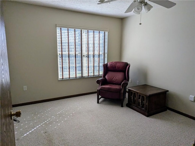 living area with ceiling fan, baseboards, carpet floors, and a textured ceiling