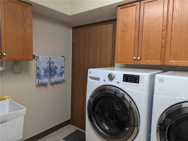 laundry room featuring a sink, baseboards, cabinet space, and independent washer and dryer