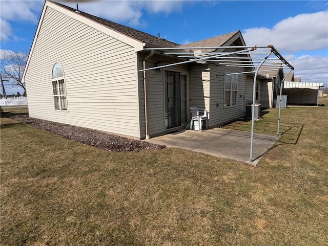 view of side of property featuring a patio area, central air condition unit, a yard, and roof with shingles