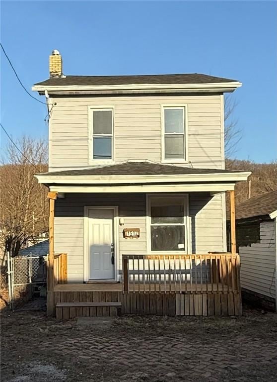 view of front of property with a porch, fence, and a chimney