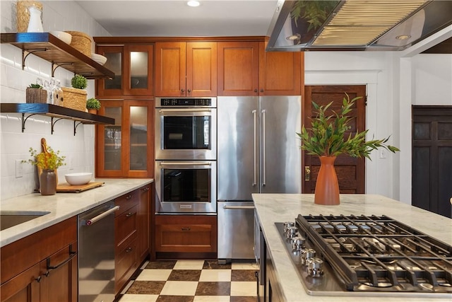 kitchen with light floors, glass insert cabinets, appliances with stainless steel finishes, exhaust hood, and backsplash