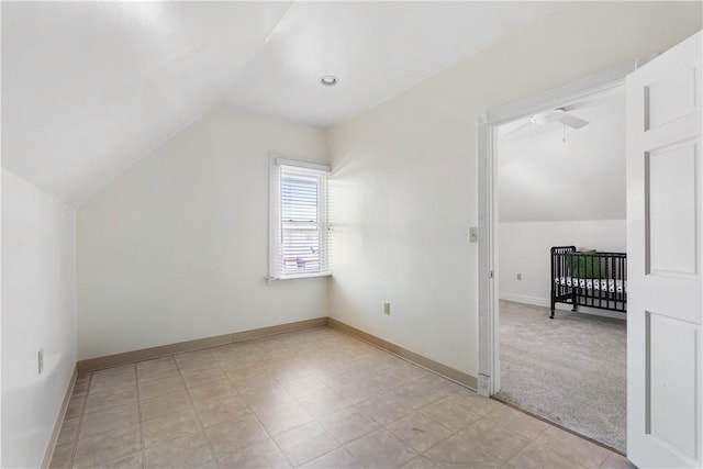 additional living space with vaulted ceiling, light colored carpet, and baseboards