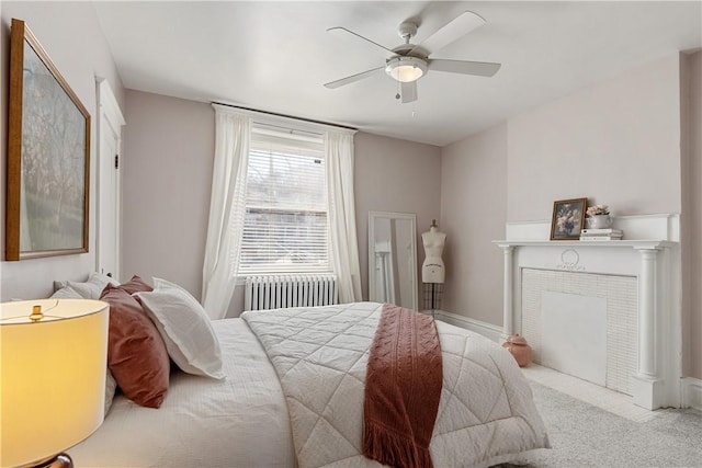 bedroom with radiator heating unit, a fireplace, carpet floors, and ceiling fan