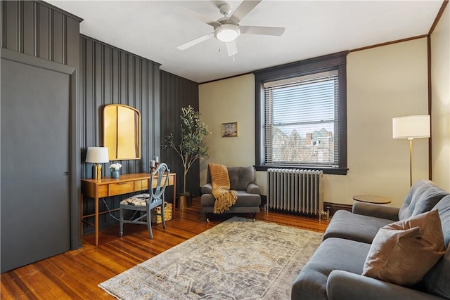 living area featuring crown molding, radiator heating unit, wood finished floors, and ceiling fan