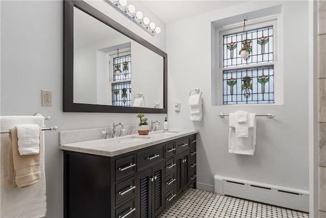 full bath featuring a sink, a baseboard radiator, baseboards, and double vanity