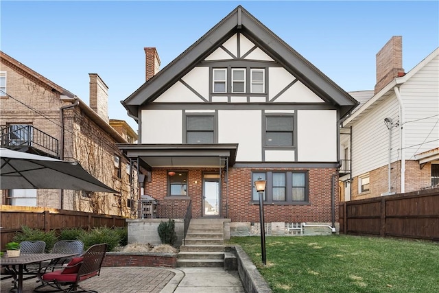 rear view of house with fence, a yard, stucco siding, a patio area, and brick siding