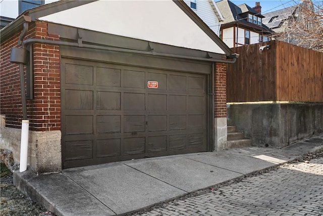 garage featuring driveway and fence