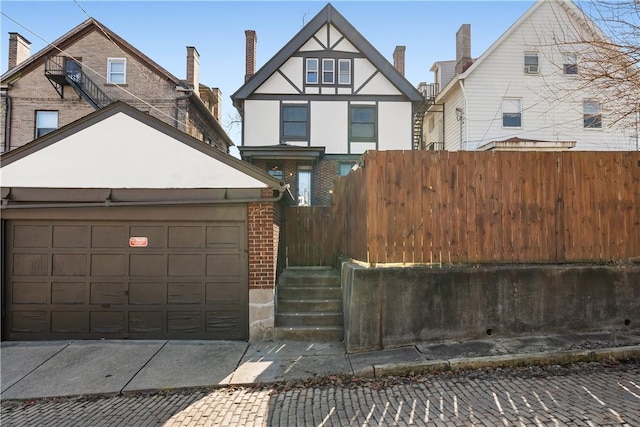 view of front of home with brick siding, fence, stucco siding, a garage, and driveway