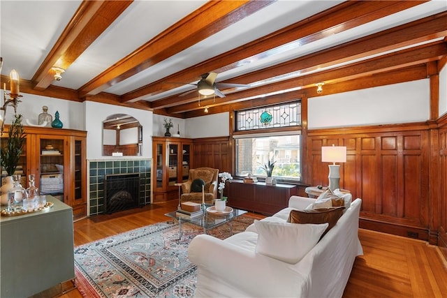 living room with ceiling fan, beam ceiling, wood finished floors, and a fireplace