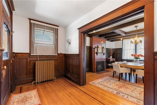 interior space featuring a notable chandelier, wainscoting, light wood-type flooring, and radiator heating unit