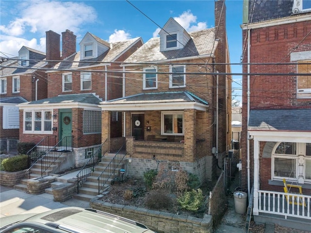 multi unit property featuring brick siding, covered porch, and a chimney