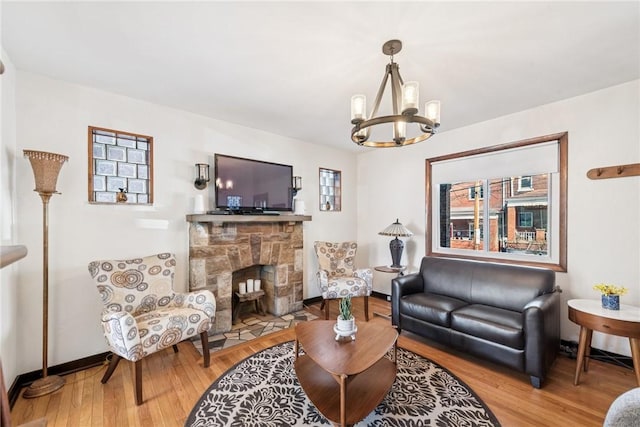 living area featuring a fireplace, an inviting chandelier, wood finished floors, and baseboards