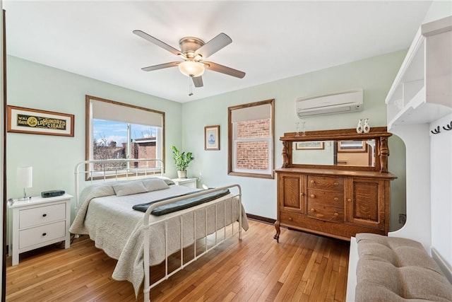 bedroom featuring ceiling fan, light wood-style floors, baseboards, and a wall mounted AC