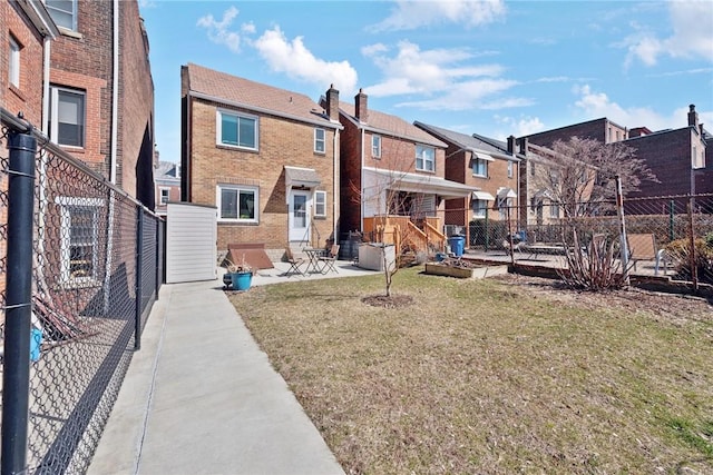 rear view of property with a patio, fence, a yard, a residential view, and brick siding