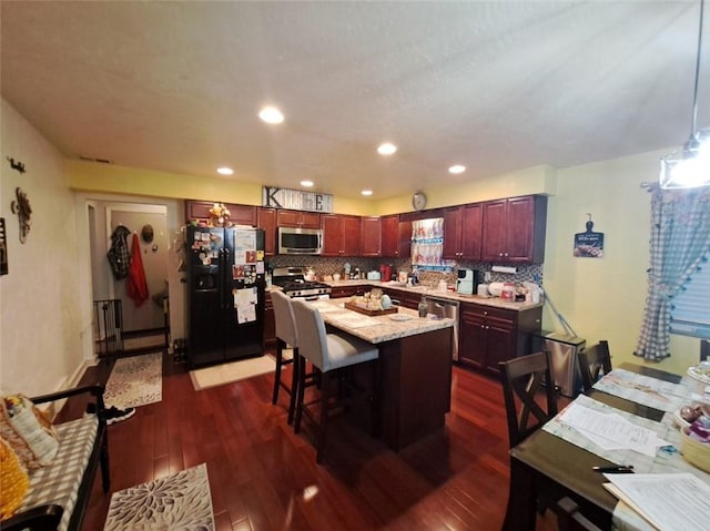 kitchen featuring tasteful backsplash, a center island, dark wood-type flooring, a kitchen breakfast bar, and stainless steel appliances