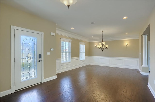 entryway with decorative columns, ornamental molding, dark wood-style flooring, and a chandelier