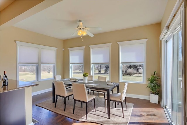 dining room featuring ceiling fan, baseboards, and dark wood-style floors