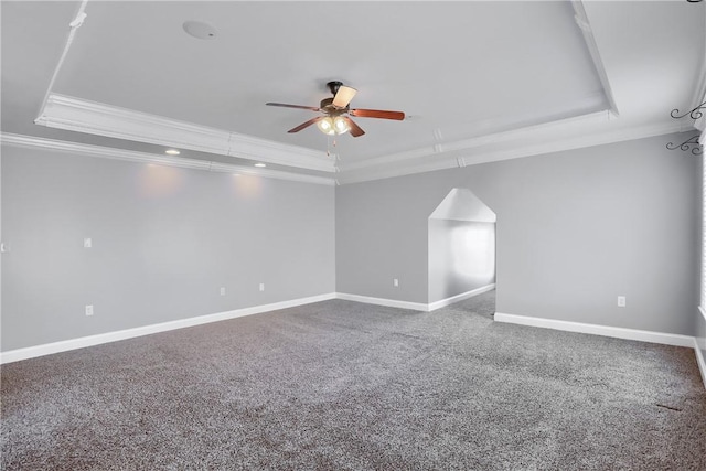 carpeted spare room with a tray ceiling, crown molding, a ceiling fan, and baseboards