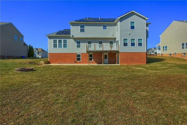 back of property featuring brick siding, a fire pit, and a yard