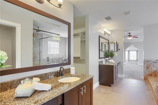 full bathroom with visible vents, baseboards, two vanities, a stall shower, and a sink