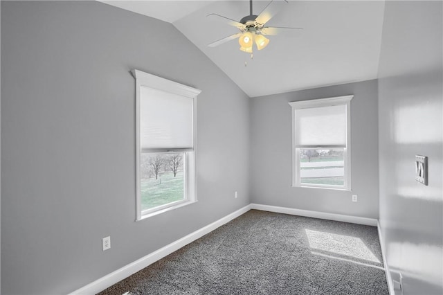 carpeted spare room featuring baseboards, plenty of natural light, ceiling fan, and vaulted ceiling