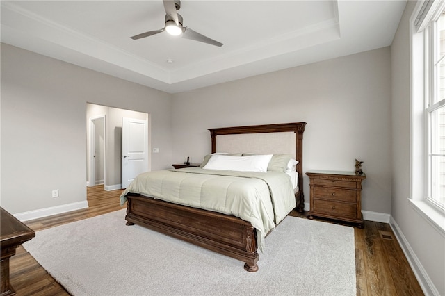 bedroom featuring baseboards, a tray ceiling, and wood finished floors