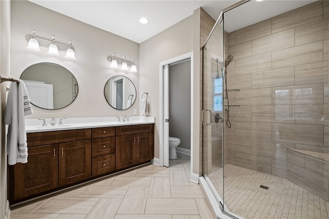 bathroom featuring double vanity, a stall shower, toilet, and a sink