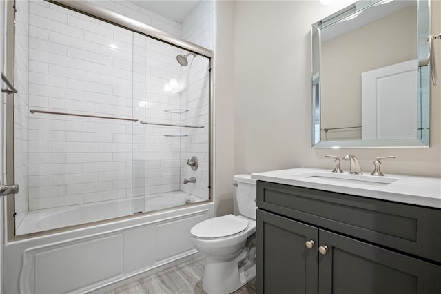 bathroom featuring combined bath / shower with glass door, toilet, and vanity