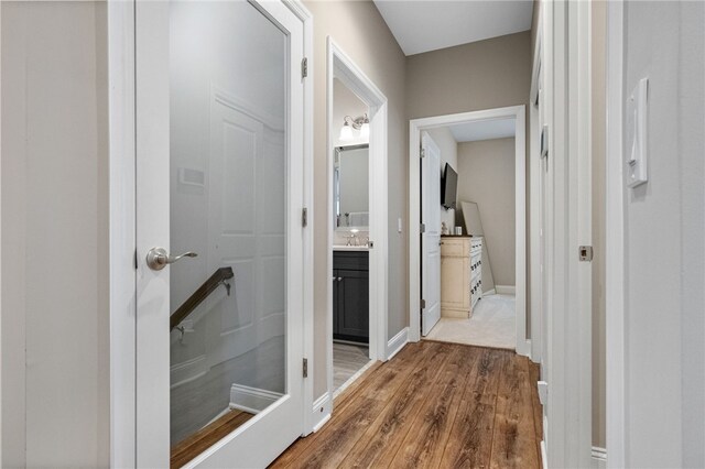 hall with a sink, baseboards, and wood finished floors