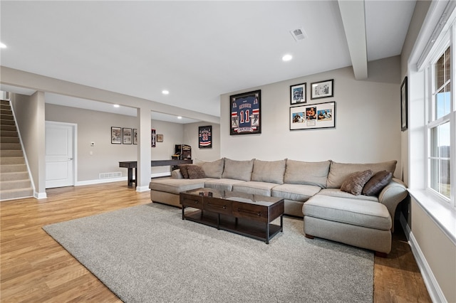 living room featuring visible vents, light wood-style floors, a healthy amount of sunlight, and stairs