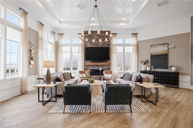 living room with a raised ceiling, wood finished floors, visible vents, and wooden ceiling