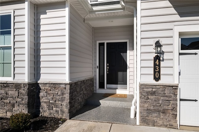 view of exterior entry with a garage and stone siding