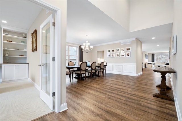 hallway with wood finished floors, visible vents, recessed lighting, crown molding, and a chandelier