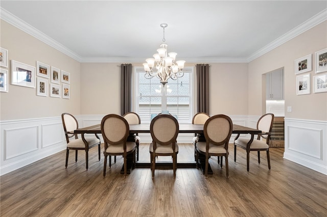 dining space with crown molding, a decorative wall, wood finished floors, and a chandelier