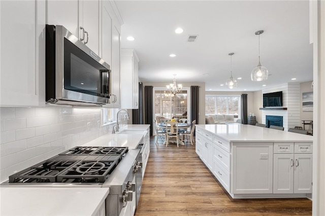 kitchen featuring visible vents, light wood-style flooring, a sink, stainless steel appliances, and white cabinetry