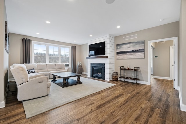 living area with wood finished floors, baseboards, visible vents, recessed lighting, and a large fireplace