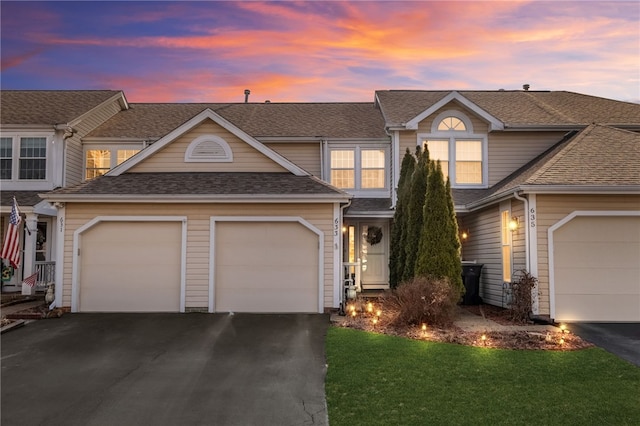 view of front of home featuring driveway, an attached garage, and a shingled roof