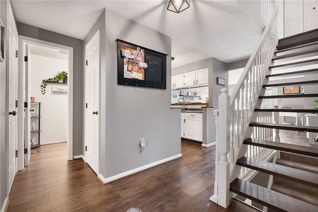 interior space with a textured ceiling, baseboards, and wood finished floors