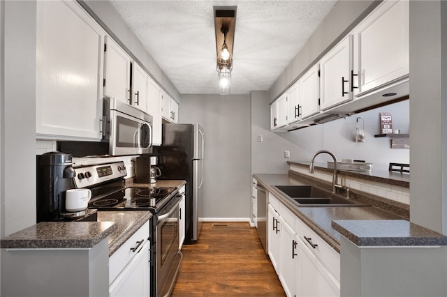 kitchen with dark countertops, appliances with stainless steel finishes, dark wood-style floors, a textured ceiling, and a sink