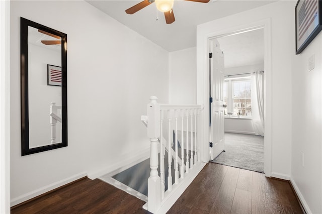 hallway with baseboards, an upstairs landing, and wood finished floors