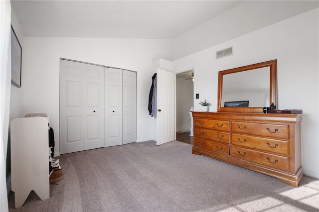 bedroom featuring a closet, visible vents, lofted ceiling, and carpet floors