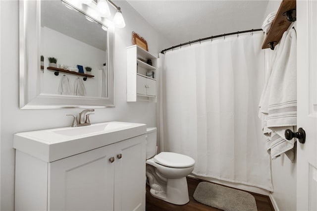 bathroom with curtained shower, toilet, wood finished floors, and vanity