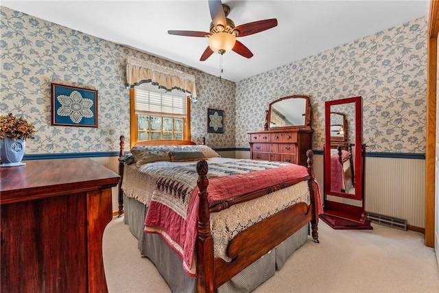 carpeted bedroom featuring wallpapered walls, a ceiling fan, a wainscoted wall, and baseboards